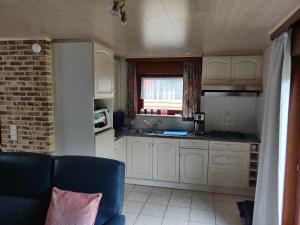a kitchen with white cabinets and a blue couch at Duinzicht in Koksijde +6 photos