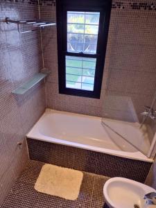 ein Badezimmer mit Badewanne und Waschbecken und einem Fenster in der Unterkunft Casa San Isidro pileta jardín parrilla a metros del río in San Isidro