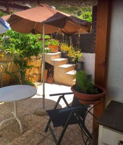 a patio with a table and an umbrella and potted plants at Kuća za odmor Kipar in Pissouri +3 photos