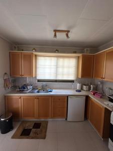 a kitchen with wooden cabinets and a sink and a window at Kuća za odmor Kipar in Pissouri
