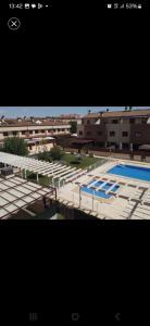 a large swimming pool with blue chairs and buildings at Duplex con piscina en barrio residencial in Albacete