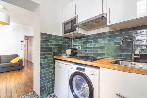 a kitchen with a washing machine and a sink at Le Charmant Bacquenois in Reims