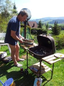 a man is cooking food on a grill at Holiday Home Tone in Frajhajm
