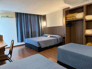 a hotel room with two beds and a desk at Afford Hotéis in Lages +42 photos