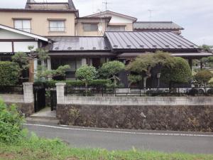 ein Haus mit einer Steinmauer neben einer Straße in der Unterkunft Minpaku Hiraizumi in Hiraizumi