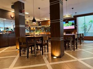 a dining room with tables and chairs and a kitchen at Afford Hotéis in Lages