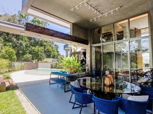 eine Terrasse mit Tisch und Stühlen und einem Pool in der Unterkunft Luxuosa Casa 5 Suítes, Piscina e Jacuzzi - Riviera in Bertioga