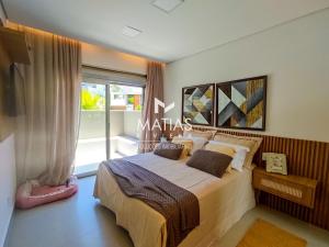 ein Schlafzimmer mit einem Bett und einem großen Fenster in der Unterkunft Luxuosa Casa 5 Suítes, Piscina e Jacuzzi - Riviera in Bertioga + 25 Fotos