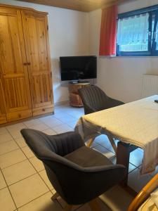 a living room with a table and chairs and a television at Pension Ernst im Herzen des Pfälzerwaldes mit Küche in Elmstein