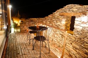 a table and two chairs on a patio at night at InXisto Lodges in Piódão