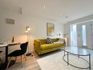 a living room with a yellow couch and a glass table at Luton Airport Area Apartment in Luton