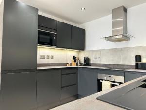 a kitchen with gray cabinets and a microwave at Luton Airport Area Apartment in Luton +18 photos