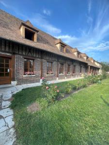 a large brick building with flowers in a yard at Au relais des diligences in Mézières-en-Vexin