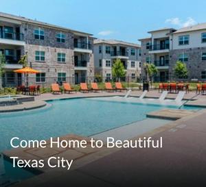 a swimming pool with chairs and tables and buildings at The LagoonSide LoungeAway in Texas City