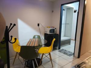 a dining room with a glass table and yellow chairs at Ice Flat Comfort in Garanhuns