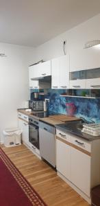 a kitchen with white cabinets and wooden floors at Cozy central APARTMENT Leopoldstrasse -3,5 rooms with sauna and garden in Munich
