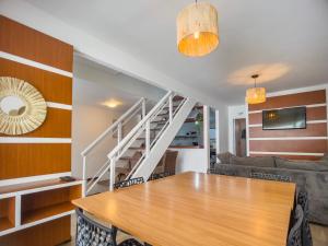 une salle à manger avec une table en bois et un escalier dans l'établissement Cabo Frio 3 Suítes, Piscina, 4 Vagas, Praia 8min, à Cabo Frio