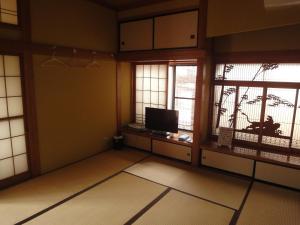 an empty room with two windows and a television at Minpaku Hiraizumi in Hiraizumi