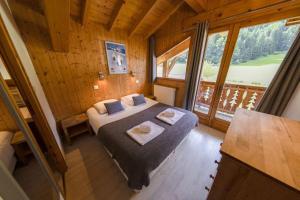 a bedroom with a bed in a room with a large window at Hauts forts Prodains Avoriaz - Mountain Voyages in Morzine +24 photos