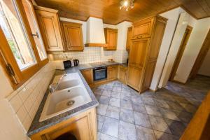 a kitchen with wooden cabinets and a sink at Hauts forts Prodains Avoriaz - Mountain Voyages in Morzine
