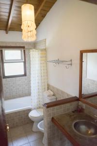 a bathroom with a toilet and a sink and a mirror at Casa La Selva in Sierra de los Padres +12 photos