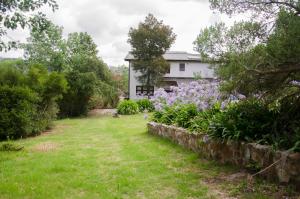 a garden with purple flowers in front of a house at Casa La Selva in Sierra de los Padres