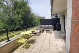 a patio with a couch and tables and chairs at Appartement avec terrasse proche gare RER in Moissy-Cramayel