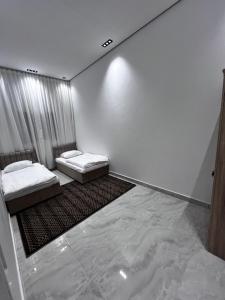 two beds in a room with white walls at استراحة لالونا in Salalah
