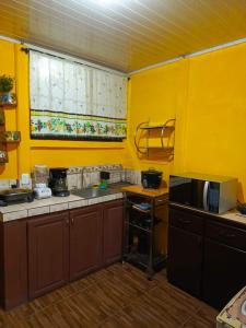 een gele keuken met een magnetron en een fornuis bij Villa Angelo Puerto Viejo in Puerto Viejo