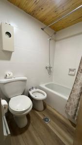a white bathroom with a toilet and a bath tub at Departamento dentro del centro de sky Valle de Las Leñas, Edificio Esparta in Las Lenas +14 photos