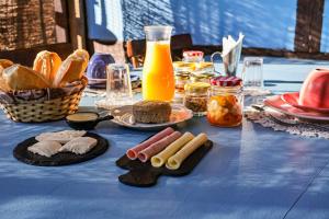 a table with a blue table cloth with food and orange juice at Com Verso e Prosa RePouso - SIMPLES e charmosa a poucos passos do centro histórico in Paraty