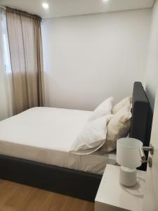 un letto con lenzuola e cuscini bianchi in una stanza di Charming Jasmin House a Viseu