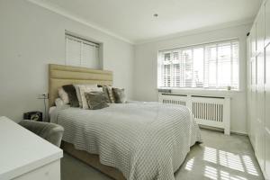 a white bedroom with a bed and two windows at Carden Villa 4 Bedroom House With Hot Tub Pet Friendly in Brighton & Hove