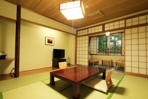 a living room with a table and chairs and a tv at Nikko Astraea Hotel in Nikko