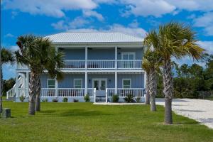 a blue house with palm trees in front of it at Blue Ocean Breeze in Mexico Beach