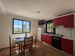 a kitchen with red cabinets and a small table with a tableablish at Recuncho de Tatá in Camariñas