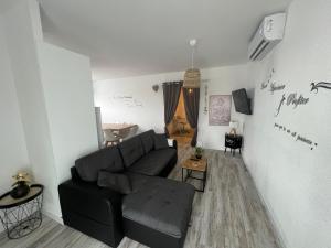 Una sala de estar con un sofá negro y una mesa. en L'Évidence, en Saint-Raphaël