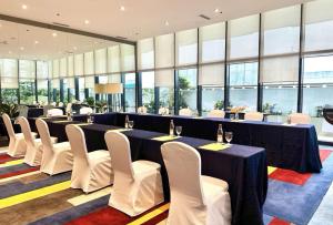a conference room with tables and white chairs and windows at Park Inn by Radisson North Edsa in Manila +66 photos