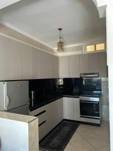 a kitchen with white cabinets and black appliances at Beachhouse Asilah in Asilah +9 photos