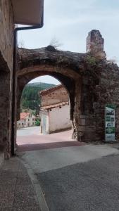 un arco in un vecchio edificio in pietra con un edificio di El descanso de las hadas a San Leonardo de Yagüe