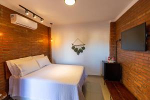 a bedroom with a white bed and a brick wall at Pousada Bem Viver - Charme e Conforto in Nobres