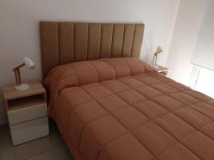 a bedroom with a large bed with an orange comforter at Ohiggins Bahía Premium in Bahía Blanca