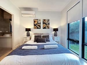 a bedroom with a large bed with a blue blanket at Luxury Glen Waverley Townhouse 4br3ba Backyard in Glen Waverley