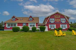 a red house with yellow chairs in front of it at Auberge Doucet Inn in Chéticamp