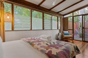 a bedroom with a bed in a room with windows at Garden Burees in Byron Bay