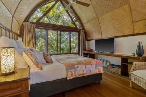 Un dormitorio con una cama y una ventana grande. en Garden Burees, en Byron Bay