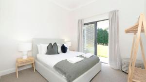 a white bedroom with a bed and a window at Silos in East Kangaloon