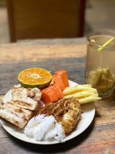 a plate of food with meat and vegetables and a drink at Banana Homestay in Banyuwangi