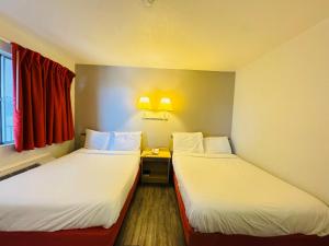 卡斯珀Studio 6 Casper WY的一间带窗户的小房间里有两张床