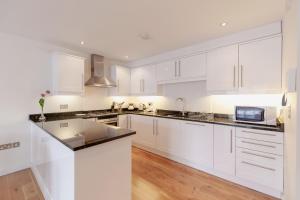 a white kitchen with white cabinets and a microwave at Roomspace Serviced Apartments - Marquis Court in Epsom